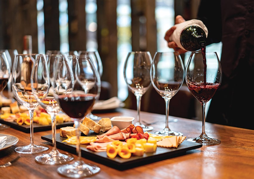 Rooftop Wine Bar at West Bay Club Wine being poured beside charcuterie and cheese boards during a tasting event at West Bay Club